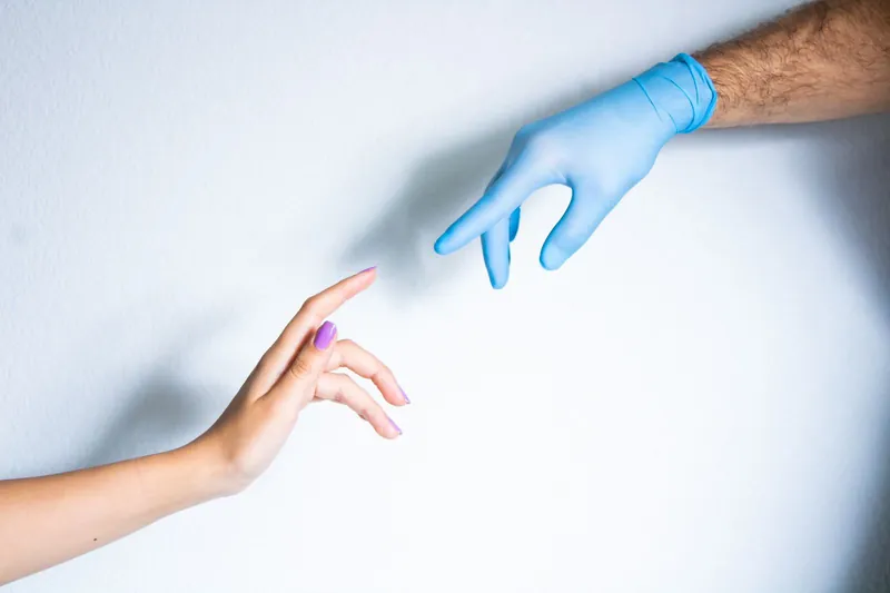 Mano de paciente y mano con guante dental, imagen de atención cercana de Alta Dental Especialidades